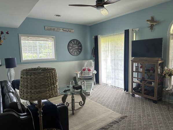A living room with a sofa, a glass coffee table, a clock, a television, and a decorative wall piece. - Cabin style 3bdrm home in Apple Canyon, walking path to the lake (Apple River)