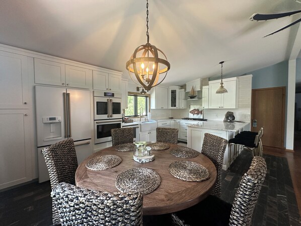 A modern kitchen with white cabinetry, a central island with woven placemats, and a hanging pendant light.