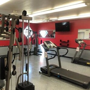 A gym with treadmills, weight machines, and a mirrored wall.