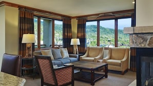 Una sala de estar con chimenea, ventanas grandes y vistas a las montañas.
