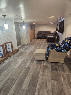 A living room with a sofa, ottoman, and wall-mounted TV. - Serene 4-bedroom house with AC in Spring Lake with old fashioned charm. (Spring Lake)