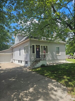 A single-story house with a front porch, a garage, and a small front yard. - Serene 4-bedroom house with AC in Spring Lake with old fashioned charm. (Spring Lake)