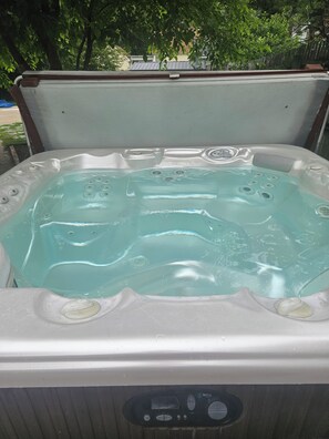 A hot tub with multiple jets, a control panel, and a clear water surface. - Serene 4-bedroom house with AC in Spring Lake with old fashioned charm. (Spring Lake)