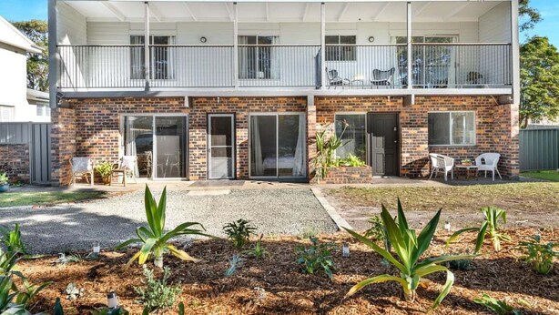 A two-story house with a balcony, a brick facade, and a front yard with plants. - Beach Street Studio Vincentia (Vincentia)