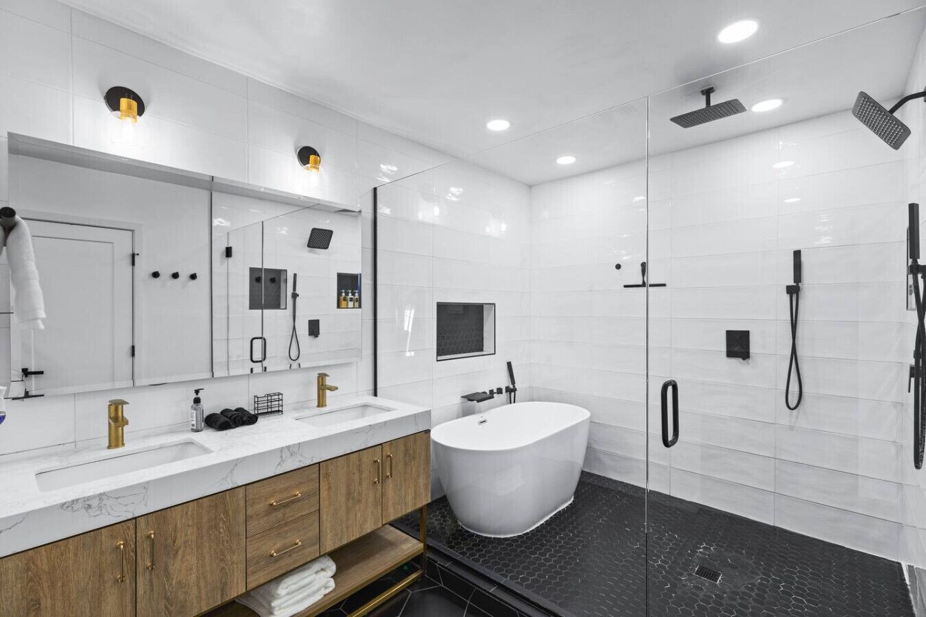 A modern bathroom with a large mirror, a freestanding bathtub, and a glass-enclosed shower area.