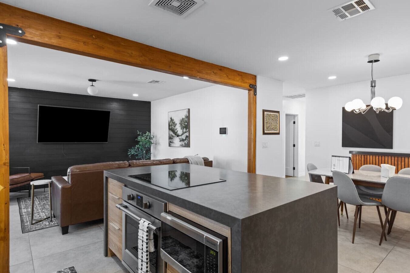 A modern kitchen with a central island, built-in oven, and a dining area with a table and chairs.