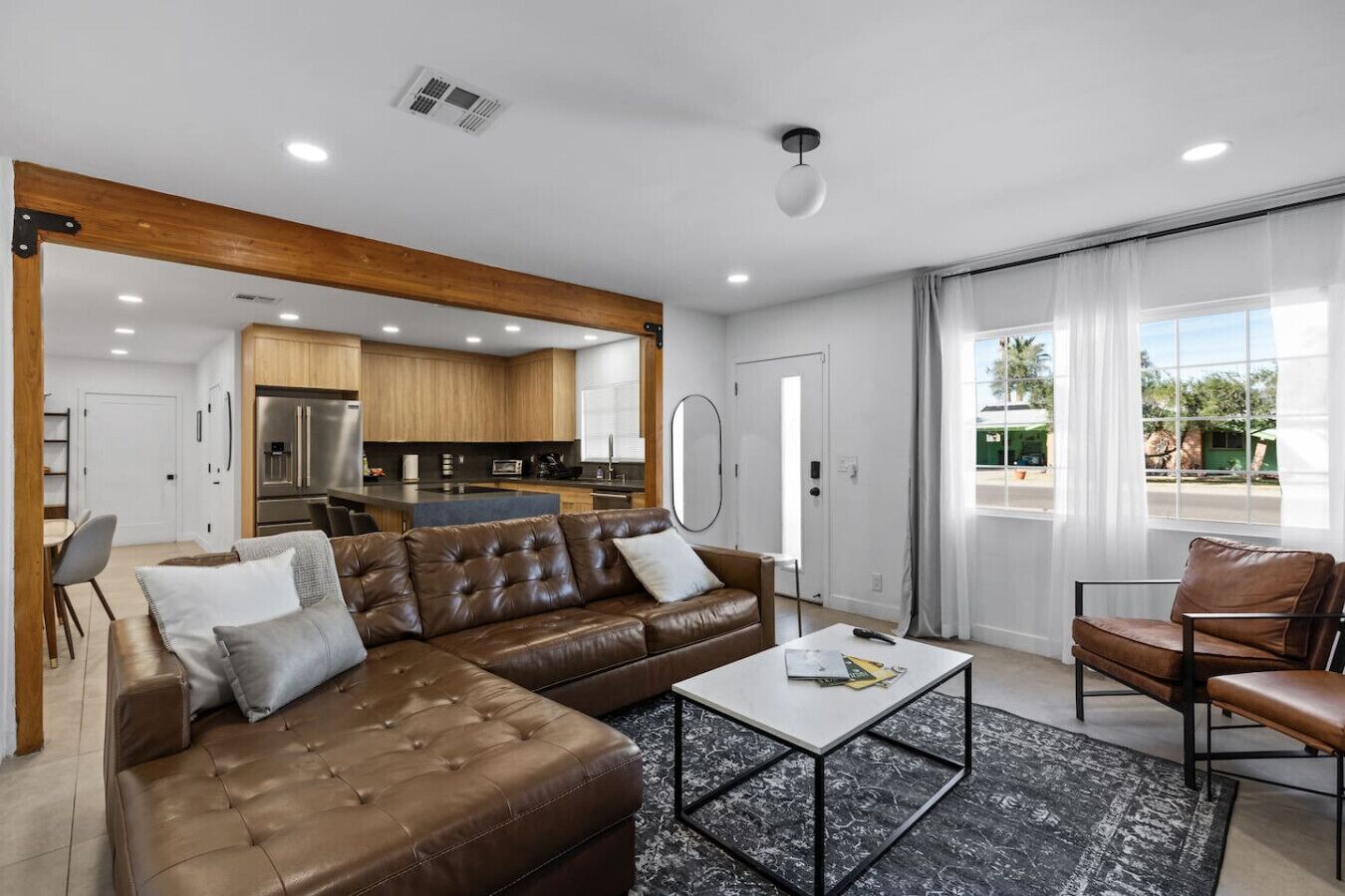 Ein modernes Wohnzimmer mit Ecksofa, Couchtisch und Essbereich, im Hintergrund eine Küche.
