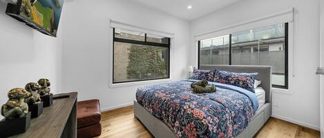 A bedroom with a bed, a dresser, a window, and a wall-mounted air conditioner.