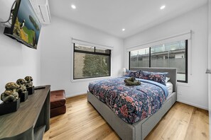 Ein Schlafzimmer mit einem Bett, einer Kommode, einem Fenster und einer Wand-Klimaanlage.