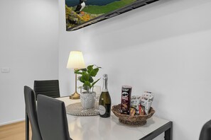 Ein Esstisch mit einer Flasche, Gläsern, einer Lampe, einer Pflanze und Snacks.