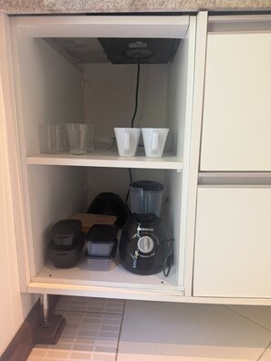 A kitchen with a built-in microwave, a blender, and a shelf with cups and containers. - Apartment 38, Ubatuba, Toninhas   (Ubatuba)