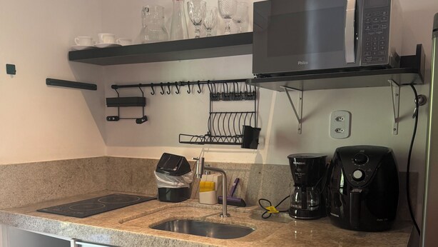 A kitchen with a granite countertop, a built-in sink, a microwave, a coffee maker, and a dish rack. - Flat 38 Ubatuba Toninhas (Ubatuba)