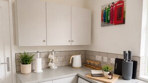 Cozinha compacta com máquina de lavar, cafeteira e uma pequena planta em vaso.