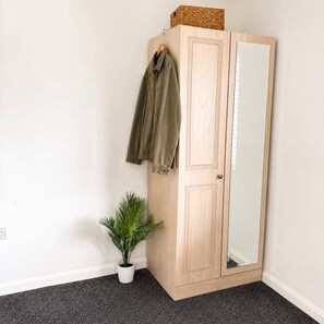 A wooden wardrobe with a mirror, a hanging jacket, and a potted plant. - Hartlepool 4BR Stay | Long Stay & Contractor Deals (Hartlepool)
