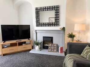 Ein Wohnzimmer mit Flachbildfernseher, Kamin, Wandspiegel und Sofa.