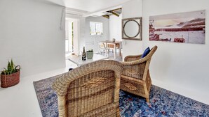 A room with a wicker chair, a dining table, and a large window. - Kommetjie Luxury Retreat for Families & Groups (Cape Town)