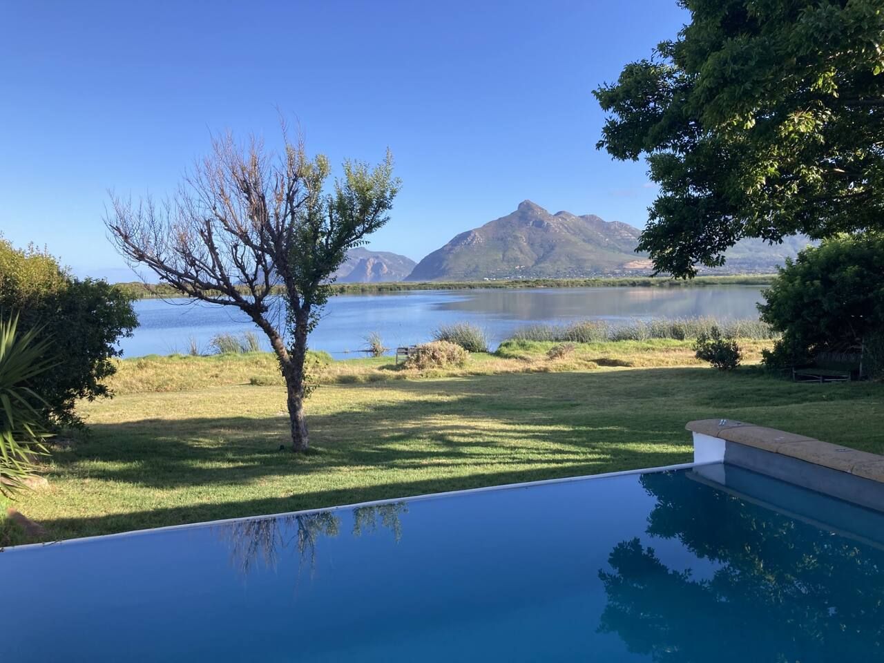A swimming pool with a view of a lake and mountains.