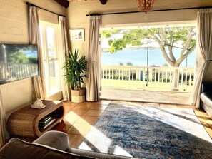 Ein Zimmer mit Blick auf Baum und Wasser, eine Couch, ein Couchtisch und eine Pflanze.