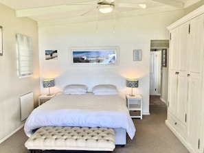 Ein Schlafzimmer mit einem großen Bett, zwei Nachttischen, einer Bank und einem Kleiderschrank.