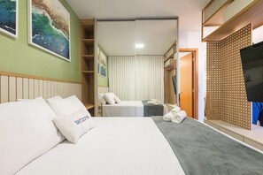 Ein Hotelzimmer mit einem Bett, einem zusätzlichen Bett, einem Fernseher, einem Kleiderschrank und einem Bild an der Wand.