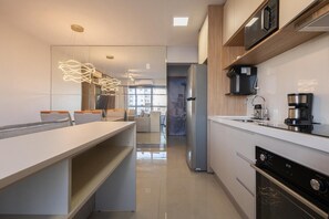 Eine moderne Küche mit Einbauofen, Kaffeemaschine und Kühlschrank.