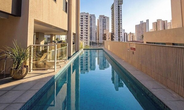 A swimming pool with a view of high-rise buildings in the background. - Studio in Condo w/ Pool and View Rbn2106 (Goiânia)