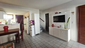 A modern kitchen with a dining area, a built-in TV, and a staircase leading to another level. - Retreat in Maragogi: 4 Bedrooms | Space & Leisure (Barra Grande)