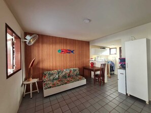 A compact living space with a wooden wall, a sofa, a dining table, and a kitchenette. - Retreat in Maragogi: 4 Bedrooms | Space & Leisure (Barra Grande)