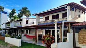 A two-story house with a balcony, a hammock, and a small garden area. - Retreat in Maragogi: 4 Bedrooms | Space & Leisure (Barra Grande)
