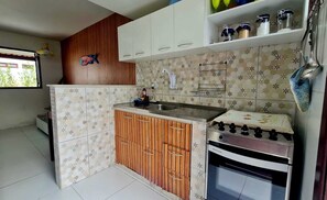 Cocina compacta con estufa, fregadero y armarios de madera.