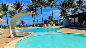 Ein Pool mit geschwungener Kante, umgeben von Palmen und Liegestühlen.