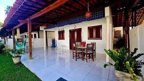 Un patio cubierto con suelo de baldosas, una mesa de comedor con sillas y una hamaca.