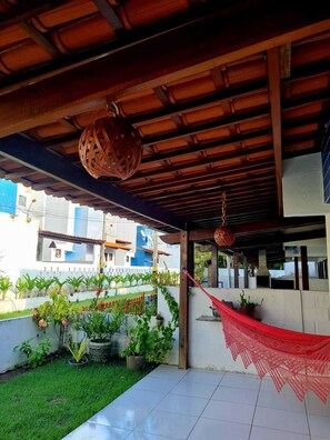 A covered outdoor area with a hammock, potted plants, and a tiled floor. - Retreat in Maragogi: 4 Bedrooms | Space & Leisure (Barra Grande)
