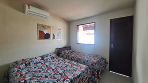 Una habitación con dos camas, aire acondicionado, una ventana y una puerta.