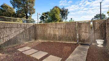 A fenced outdoor area with a gravel path and a stone bench.