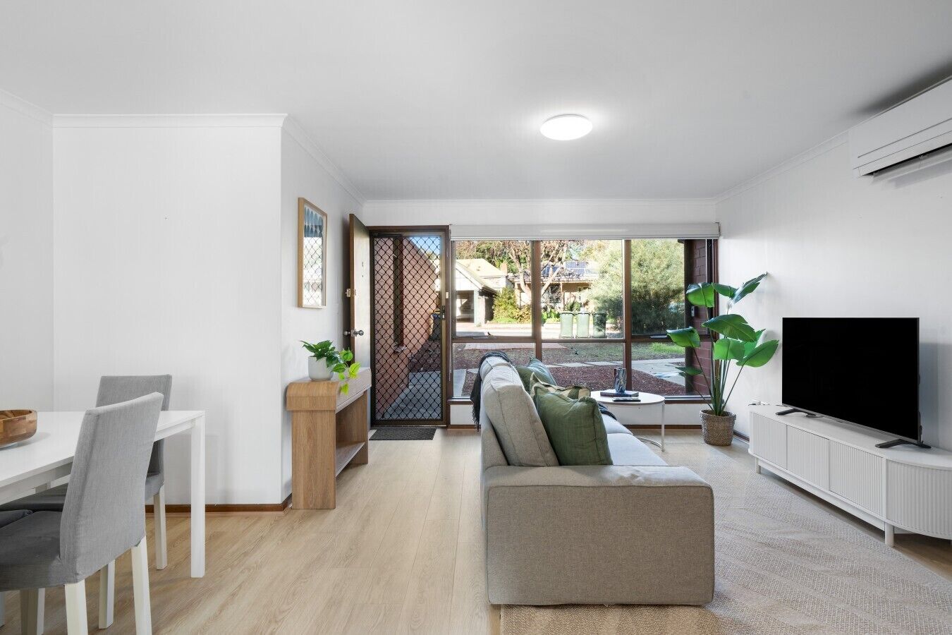 Una sala moderna con sofá, televisión y comedor.