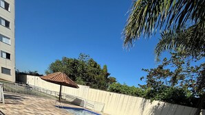 A swimming pool with a tiled deck, surrounded by a white wall and a palm tree. - Ocean leisure (São Vicente)