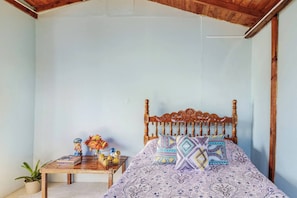 A bedroom with a wooden bed, a small bedside table, and a potted plant. - Cabaña el Sol Medellin (Titiribí)