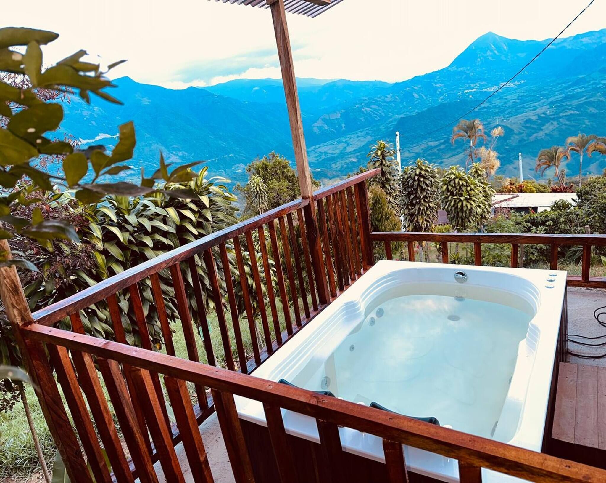Una vasca idromassaggio su un pontile di legno con vista sulle montagne.