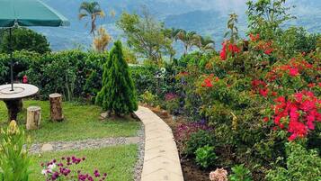 A garden pathway with a view of mountains, surrounded by various plants and flowers.