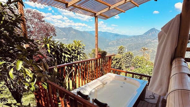 Jacuzzi en una terraza de madera con vista a las montañas.