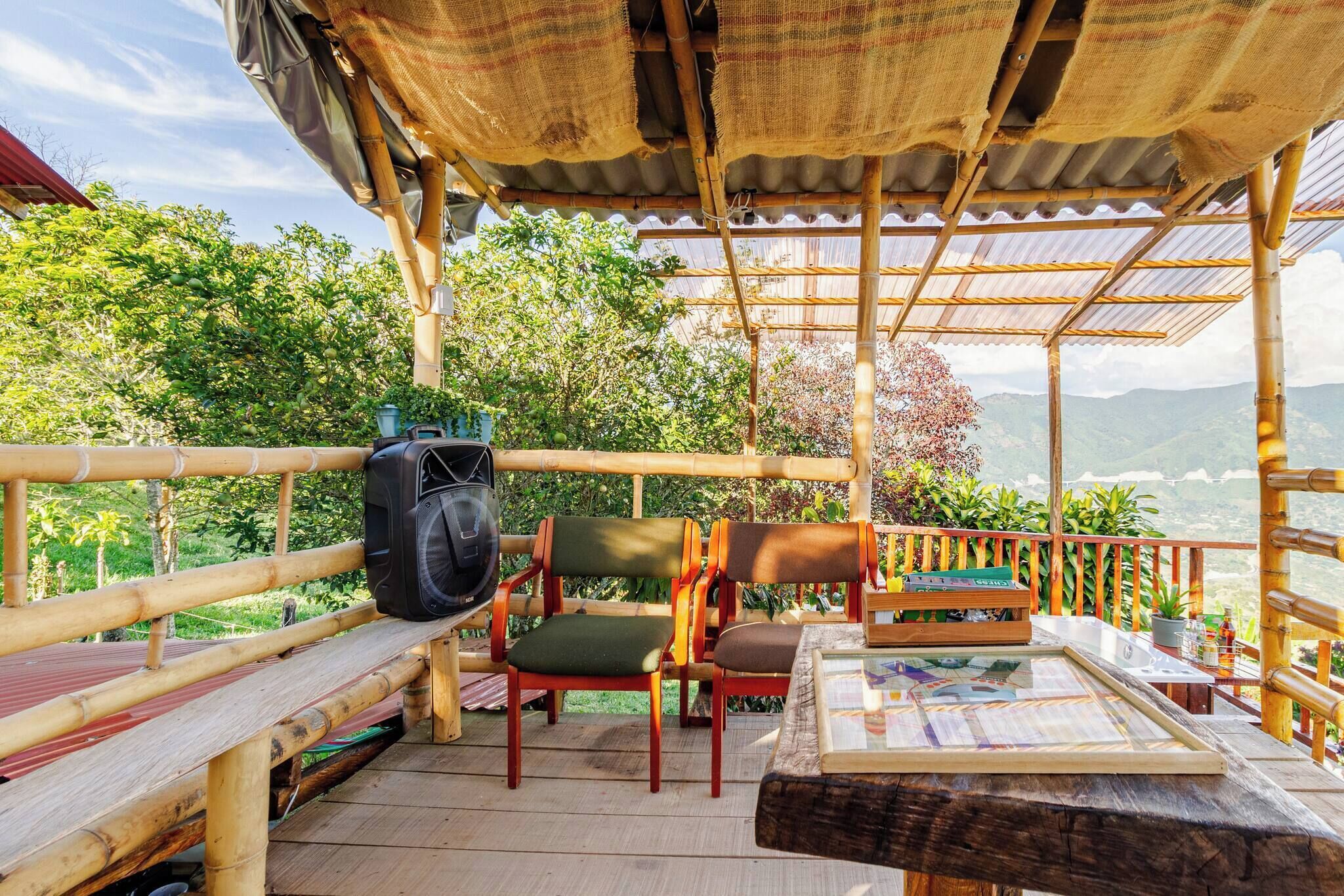 A covered outdoor seating area with chairs and a table, overlooking a lush landscape.