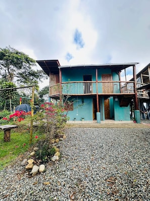 A two-story building with a balcony, surrounded by a gravel driveway and greenery. - Cabaña el Sol Medellin (Titiribí)
