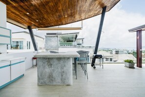 A rooftop terrace with a concrete bar area, wicker chairs, and a grill. - Panoramic Seaview Elevate Villa, Infinity Pool (Rawai)