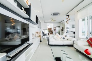 A modern living room with a sofa, TV, and a dining area. - Panoramic Seaview Elevate Villa, Infinity Pool (Rawai)