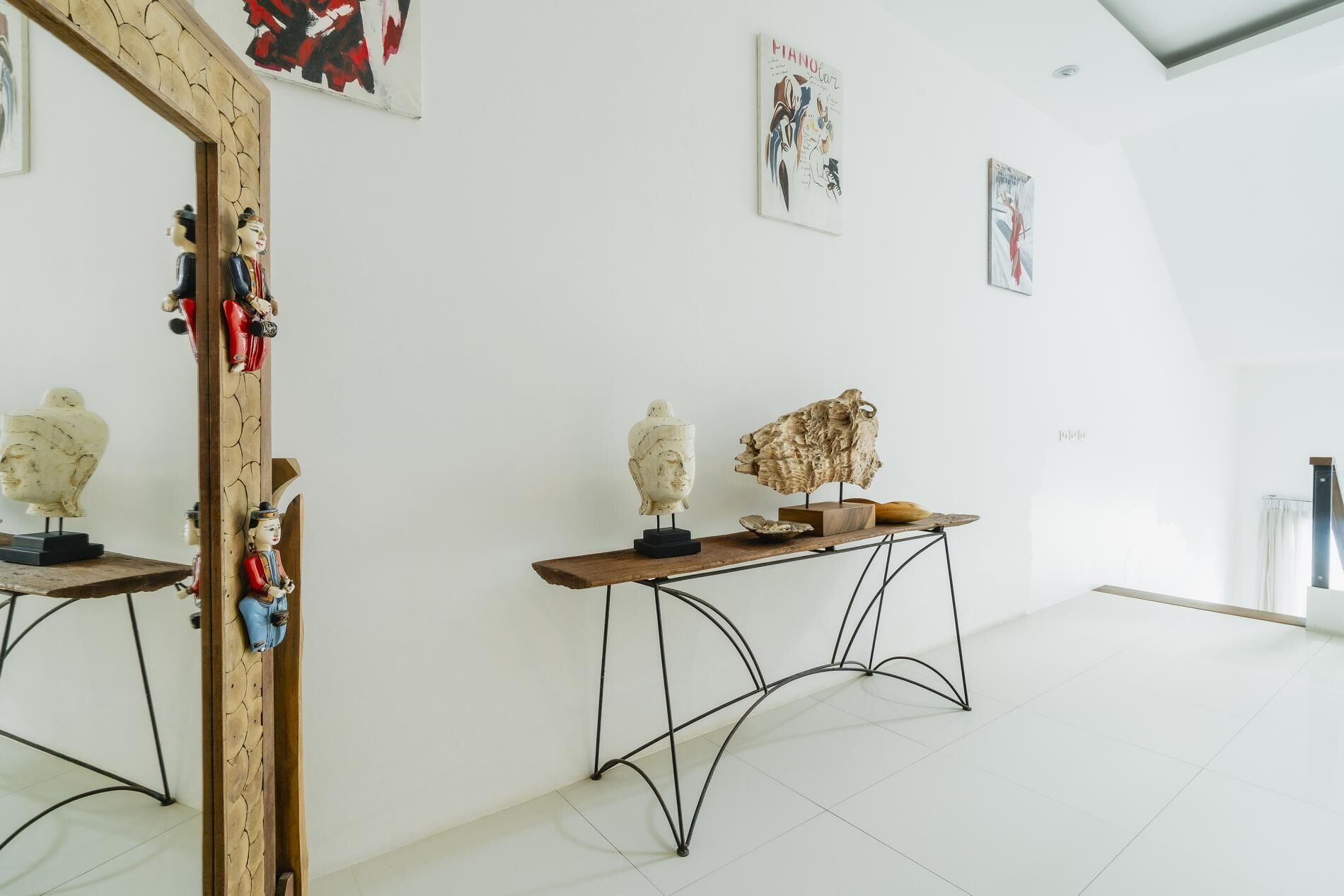 Un espace galerie minimaliste avec des murs blancs, un grand miroir et des œuvres d’art abstraites.