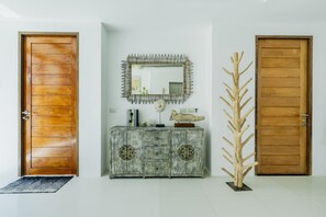 Ein Flur mit zwei Holztüren, einem rustikalen Holzschrank mit Verzierungen und einer einzigartigen, baumartigen Skulptur.