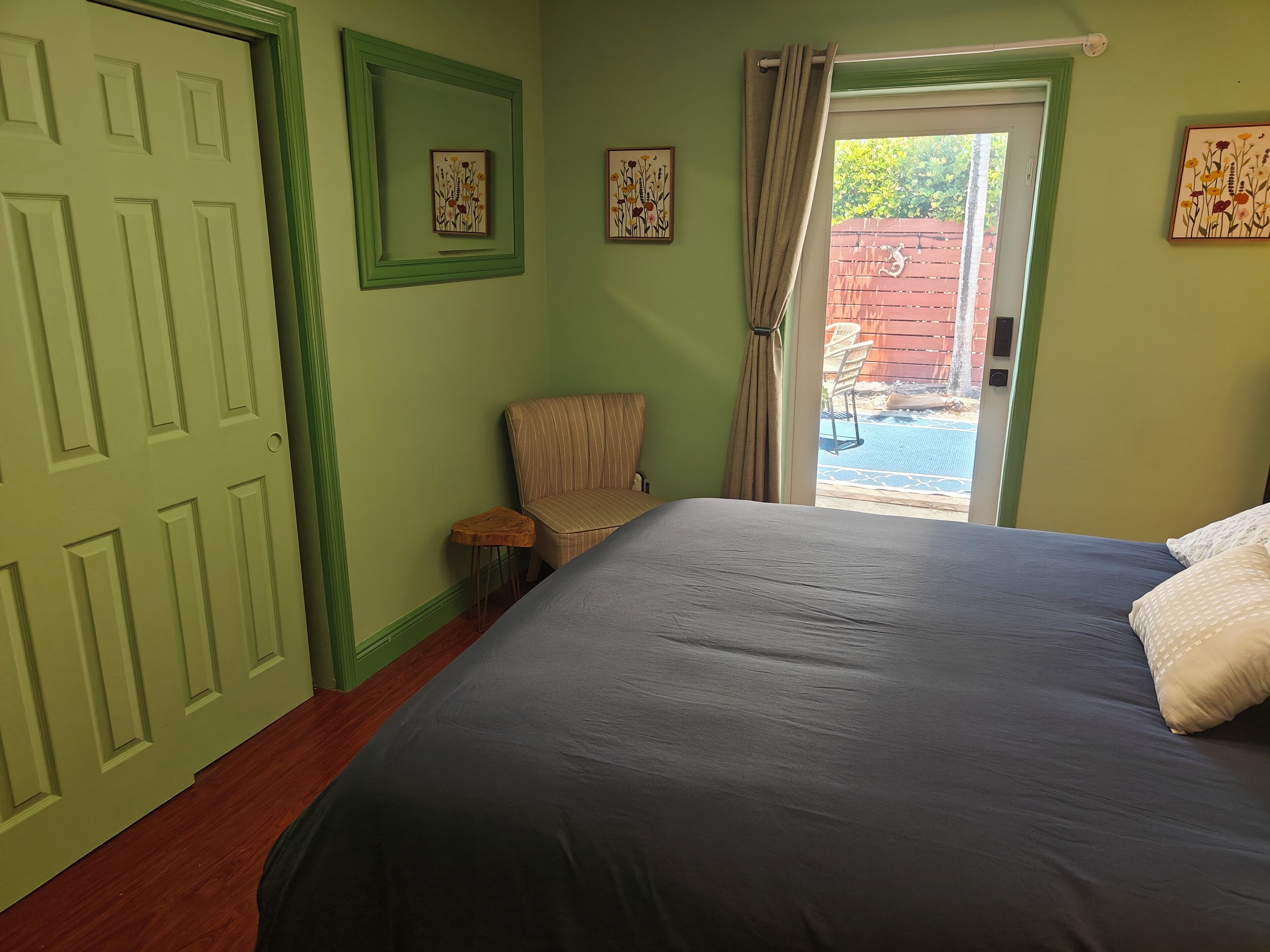 Um quarto com uma cama, uma cadeira, uma porta e vista para o exterior.