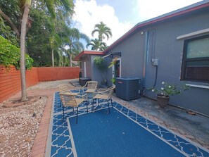 Eine Terrasse mit Gartenmöbeln, einem blauen Teppich mit Muster und einem Blumentopf.