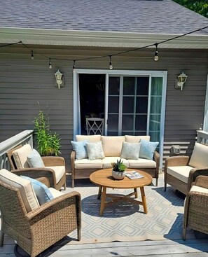 A patio with wicker furniture, a round wooden table, and a potted plant. - Luxury Woodland Retreat Game Room Sleeps 6 Near Providence (Scituate)